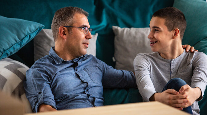 dad and son talking inside in living room by couch