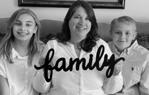 Michelle and her family pose on the couch while holding a wooden sign that says "family" in this foster care adoption success story