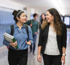 Teen in foster care walking with their teacher through a school hallway. Learn how teachers and school professionals can support youth in foster care.